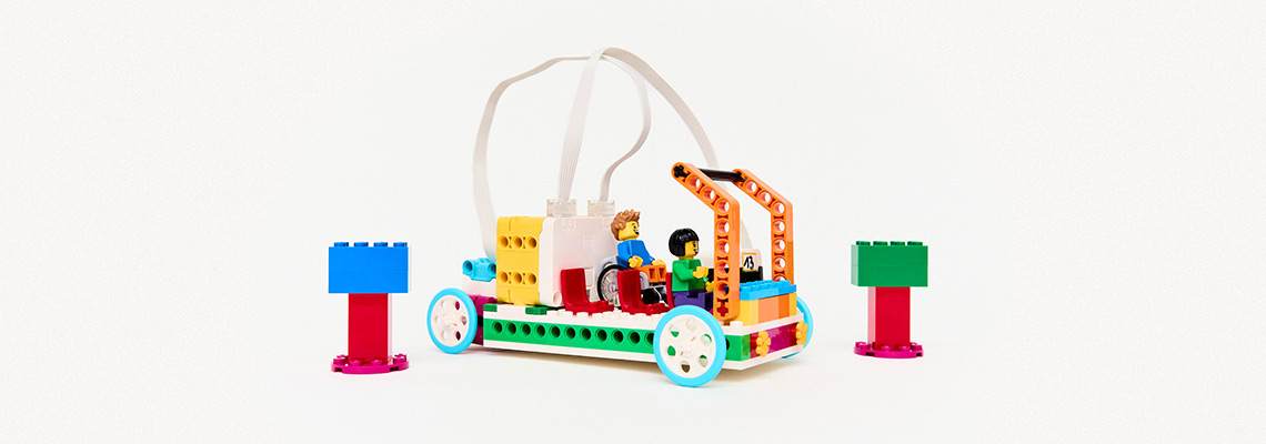 Ein gebautes Fahrzeug aus Lego mit zwei Personen als Passagiere, zwei Bäume aus Lego rechts und links